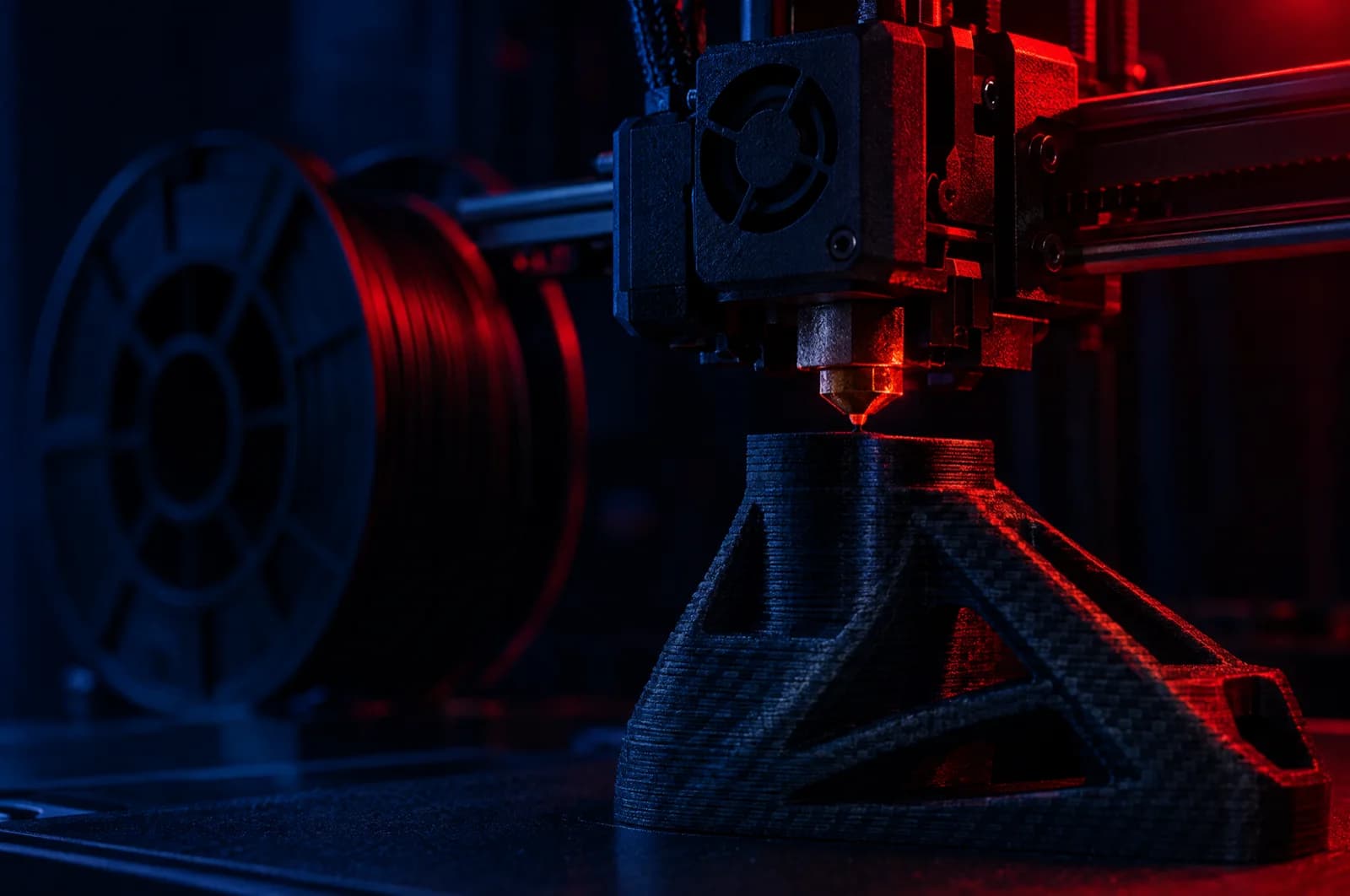 3D printer mid-print of a black carbon-fibre part