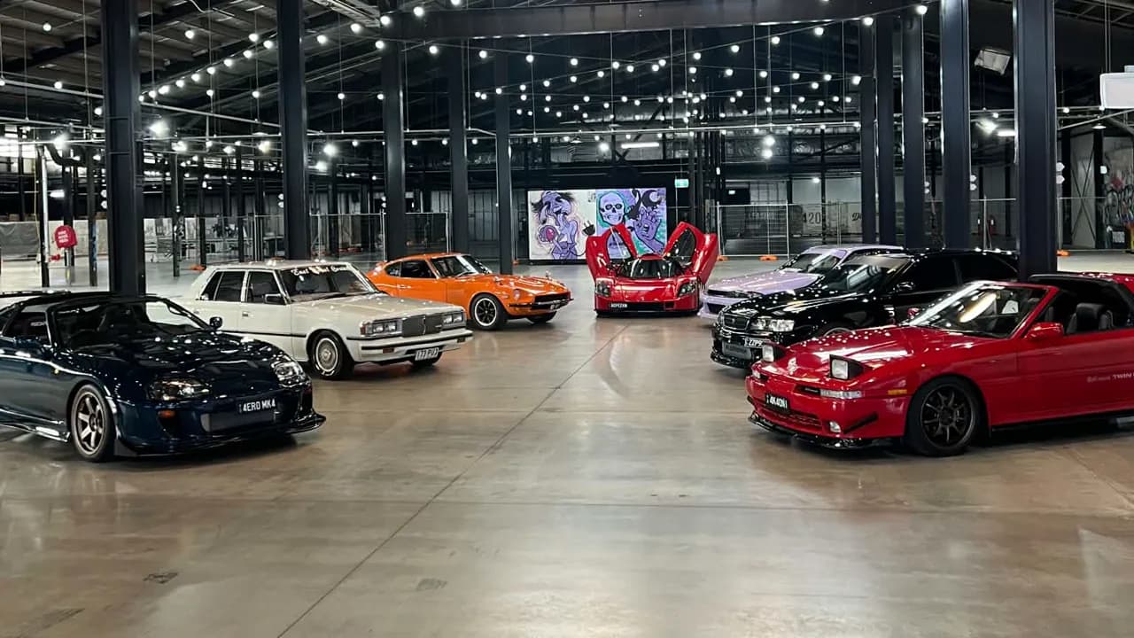 Modified Japanese performance cars lined up in a warehouse venue
