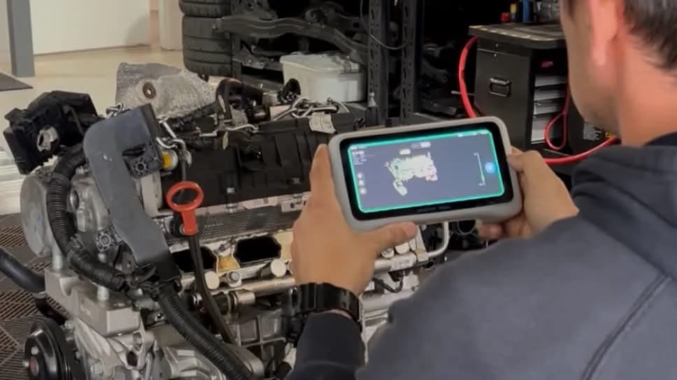 Technician scanning an engine on the workshop floor with a handheld 3D scanner