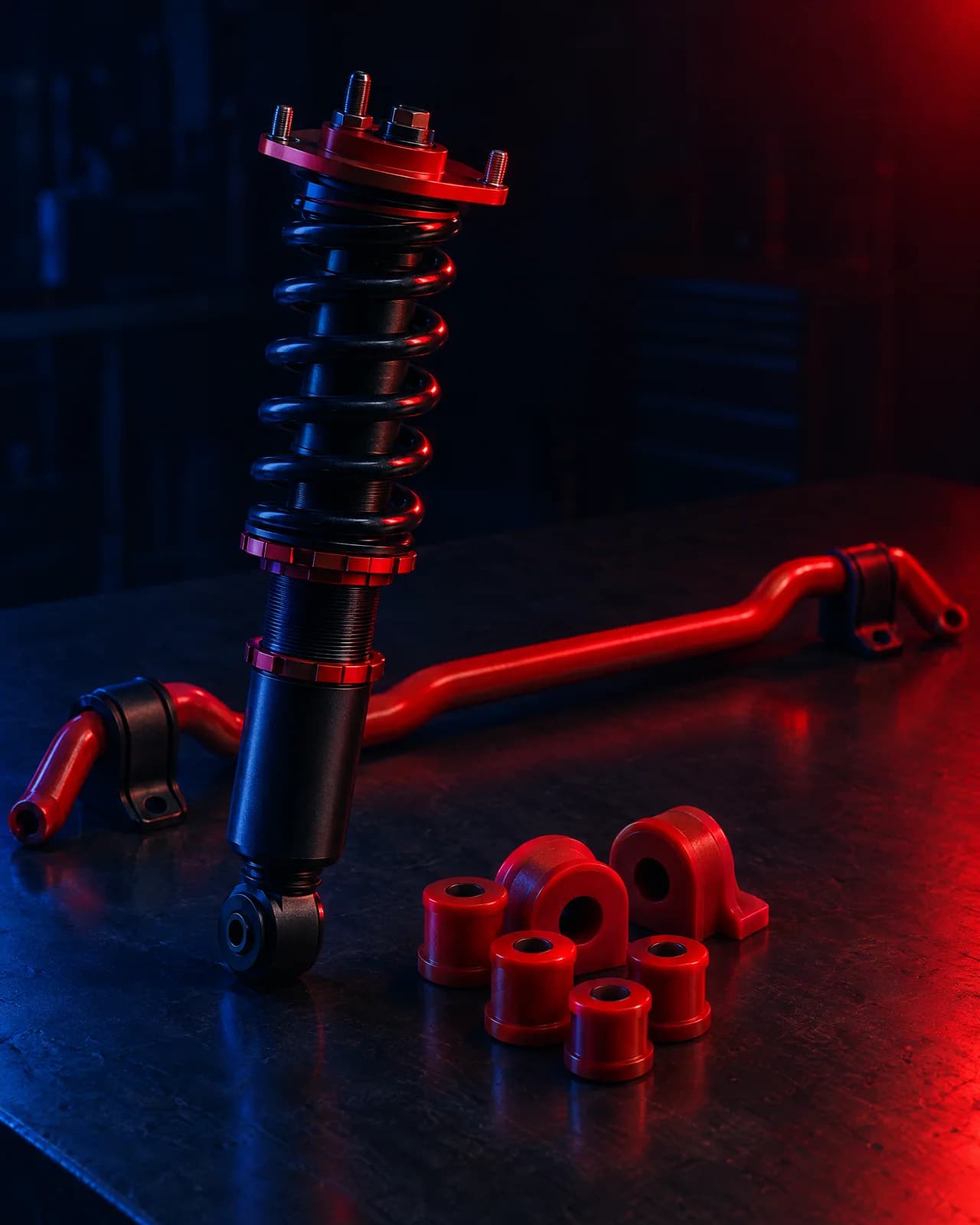 A coilover, a sway bar and a set of polyurethane bushes arranged together on a dark bench