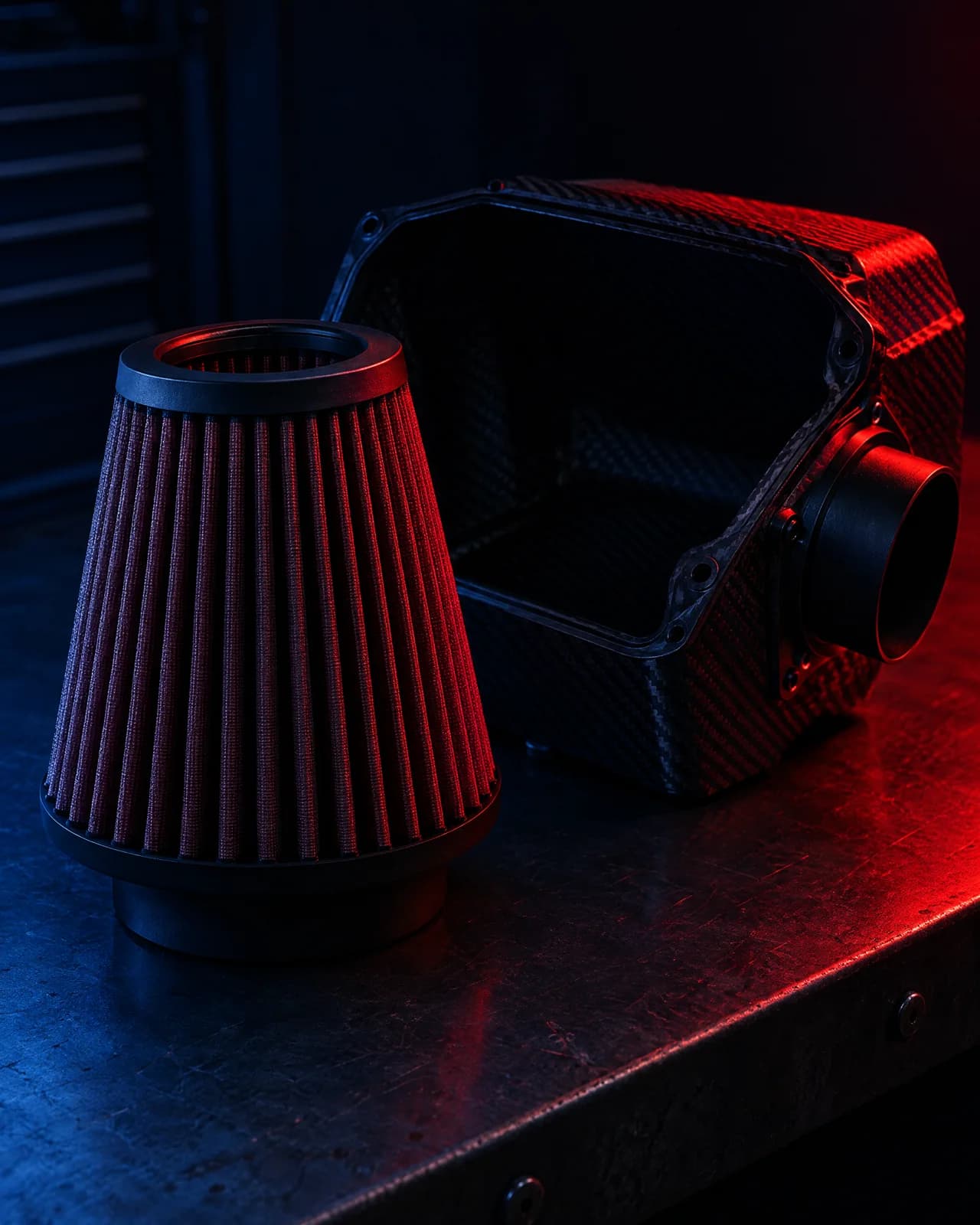 A high-flow conical air filter beside an open Roccomotive airbox on a dark bench