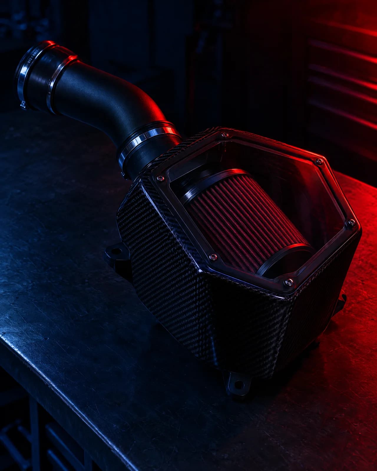 Roccomotive enclosed cold air intake system with clear lid and intake pipe on a dark bench