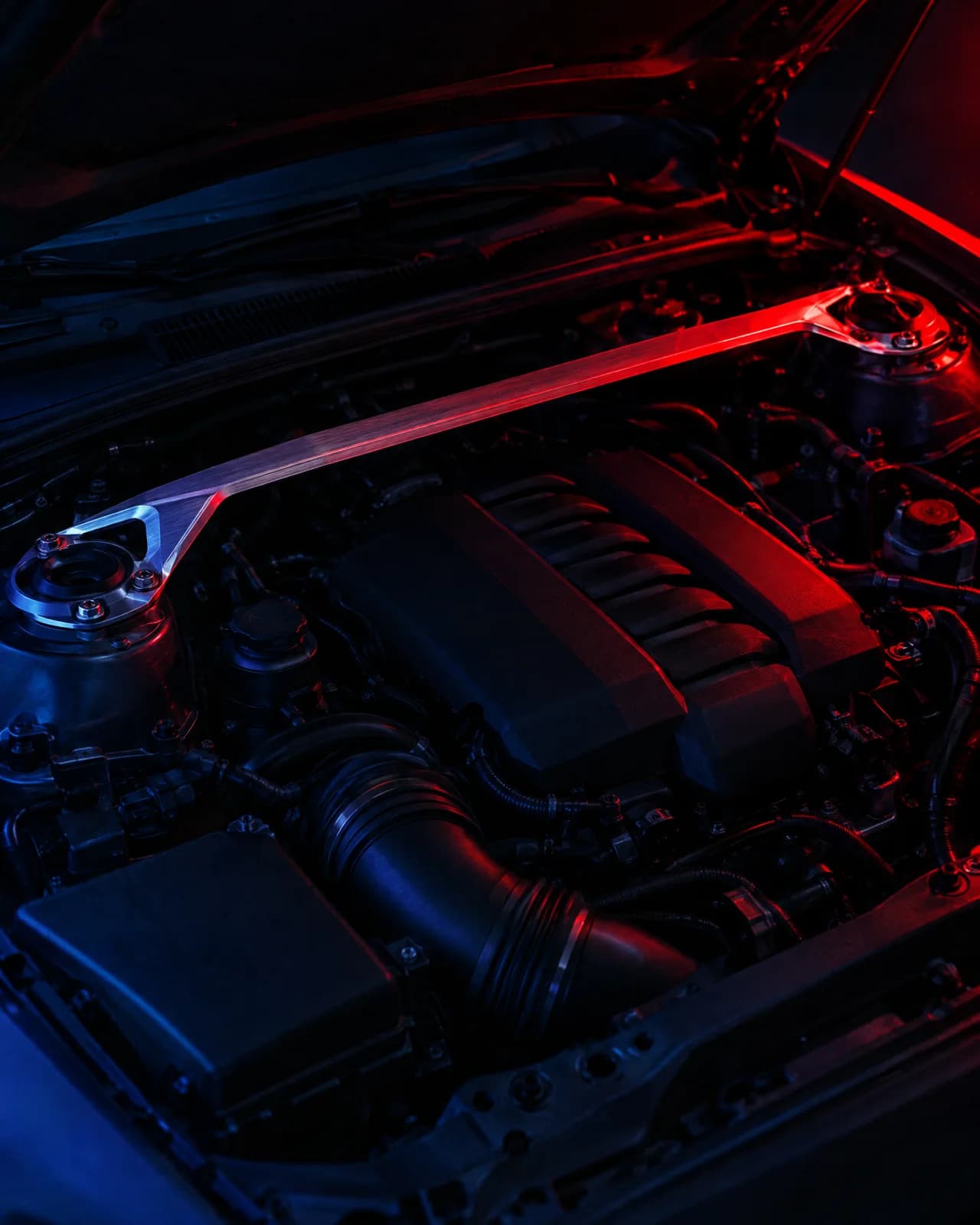 A machined aluminium strut brace across an engine bay under a red key light
