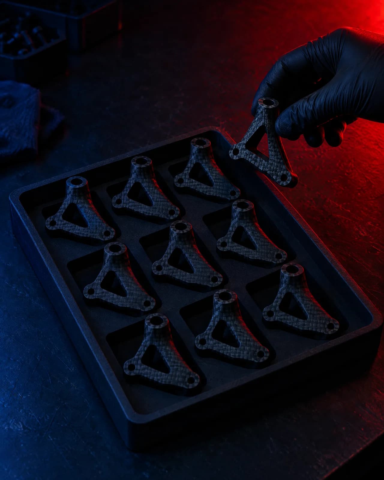 A batch of identical black printed brackets in a tray, ready for a workshop's repeat order