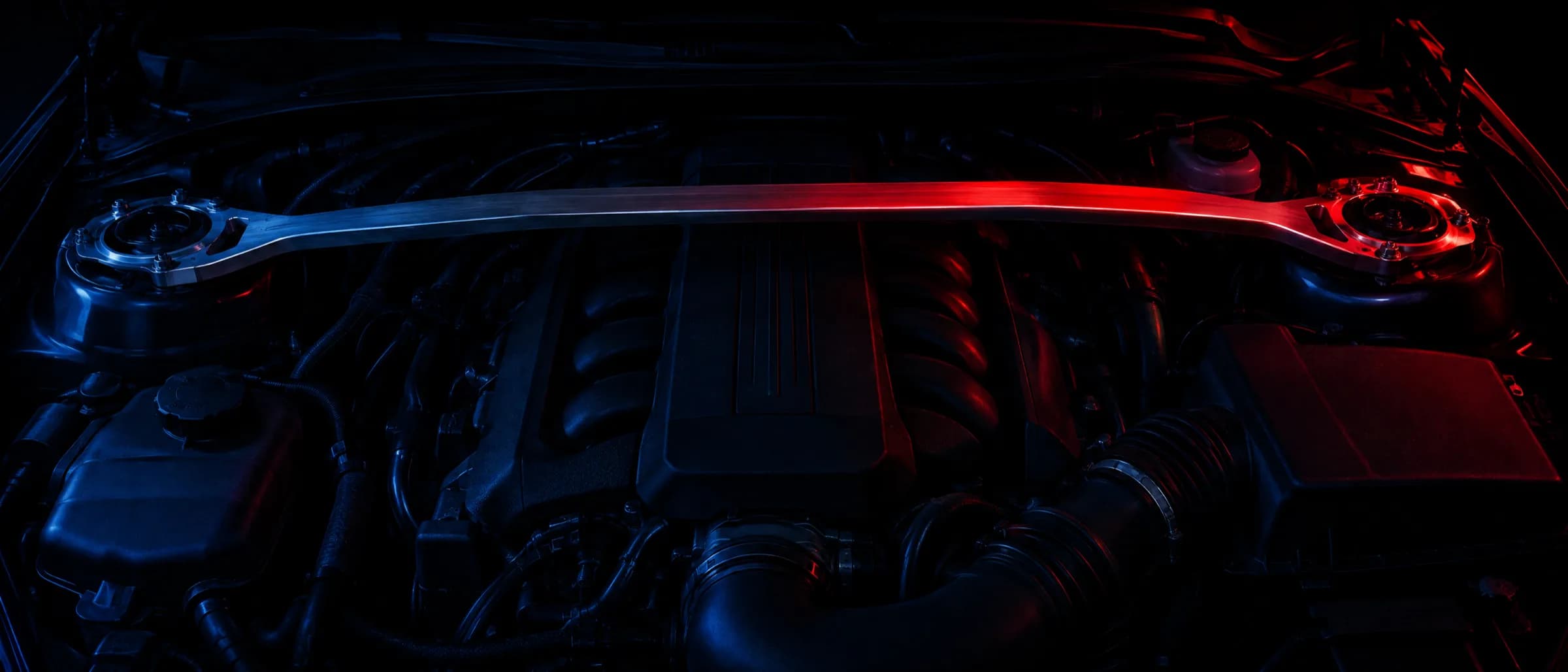 A machined strut brace spanning a dark engine bay