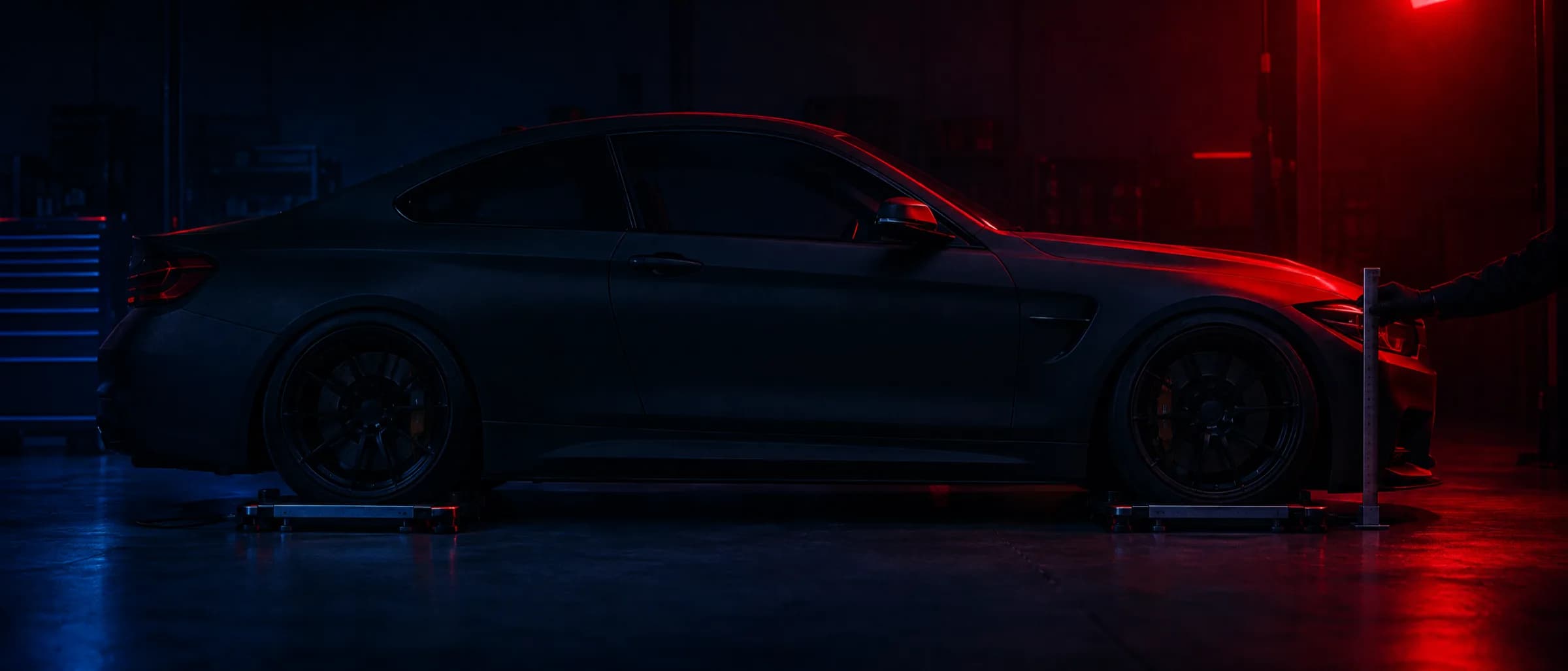 A coupe sitting low after setup, a ride-height gauge held against the guard