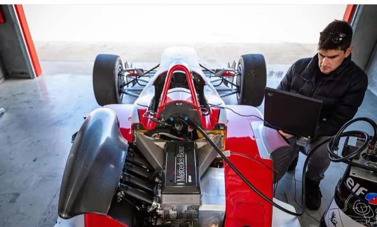 Marcello Surace working on an open-wheel race car with a laptop connected